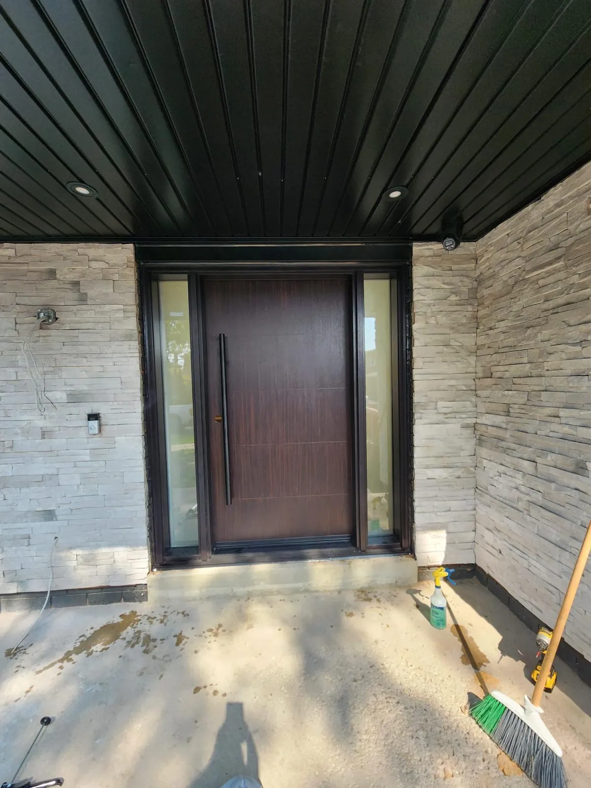 Modern entry door with two sidelites in a stacked stone surround