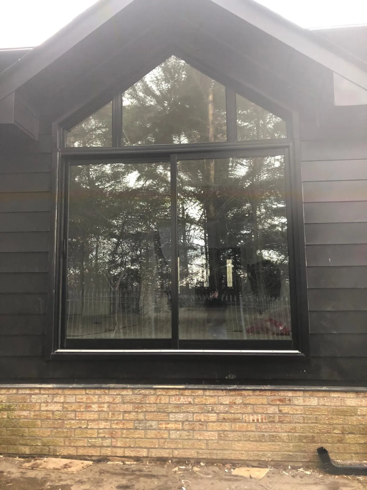 Black-framed gable window assembly on a dark clad home